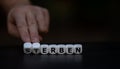 Hand turns dice and changes the German word `sterben` die to `erben` inherit. Royalty Free Stock Photo