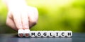 Hand turns dice and changes the German word `unmÃÂ¶glich` impossible to `mÃÂ¶glich` possible. Royalty Free Stock Photo