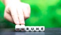 Hand turns dice and changes the German word `unruhe` restlessness to `Ruhe` silence. Royalty Free Stock Photo