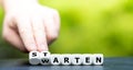 Hand turns dice and changes the German word `warten` wait to `starten` start. Royalty Free Stock Photo