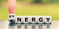 Hand turns a dice and changes the word `energy` to `synergy`, or vice versa. Royalty Free Stock Photo