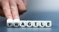 Hand turns dice and changes the word 'fragile' to 'agile'.