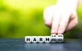 Hand turns dice and changes the word `harmful` to `harmless`.