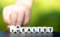 Hand turns dice and changes the word idealist to realist Royalty Free Stock Photo