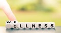 Hand turns dice and changes the word `illness` to `wellness`.