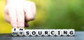 Hand turns dice and changes the word outsourcing to insourcing