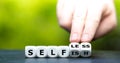 Hand turns dice and changes the word `selfish` to `selfless`. Royalty Free Stock Photo