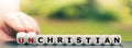 Hand turns dice and changes the word `unchristian` to `christian`.