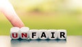 Hand turns dice and changes the word unfair to fair. Royalty Free Stock Photo