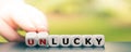 Hand turns dice and changes the word `unlucky` to `lucky`.