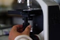 Hand turns the microscope's fine focus adjustment knob