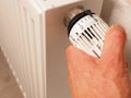 Hand turns the thermostat of a radiator, save energy, reduce energy costs