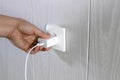 Hand turns on, turns off charger in electrical outlet on wall Royalty Free Stock Photo