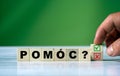 Hand turns the wooden cube and changes the polish word POMÃâC english HELP