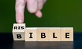 Hand turns wooden cube and changes the word bible to risible. Symbol for criticism on the bible Royalty Free Stock Photo