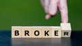 Hand turns wooden cube and changes the word broker to broke. Symbol for a wrong financial decision