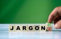 The hand turns the wooden cube and changes the word JARGON