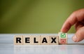 hand turns the wooden cube and changes the word RELAX with green positive tick check box and red reject X check box Royalty Free Stock Photo