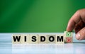 Hand turns the wooden cube and changes the word WISDOM with green positive tick check box and red reject X check box