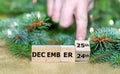 Hand turns wooden cubes and changes the date 'December 24th' to 'December 25th.