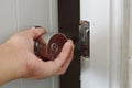 Hand twisting silver knob to opened door in dark room Royalty Free Stock Photo