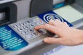 the hand types the pin code on the ATM keyboard.