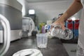 Hand of unknown woman pouring distillate water to plastic cup on the kitchen counter preparing Royalty Free Stock Photo