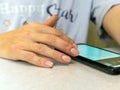 A hand of unrecognizable young caucasian woman is sitting at homeoffice tapping to smartphone`s screen Royalty Free Stock Photo