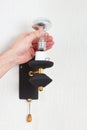 Hand unscrews incandescent lightbulb in a lamp on white wall