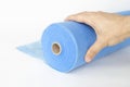 A hand unwinds a roll of blue fabric, a sheet for massage Royalty Free Stock Photo