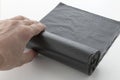 hand unwinds a roll of plastic garbage bags, a black polyethylene waste container