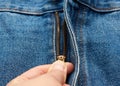 Hand unzips the iron zipper on the fly of blue jeans pants Royalty Free Stock Photo