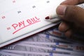 A hand uses a red marker to write Pay Bill on a white calendar date Royalty Free Stock Photo