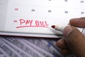 A hand uses a red marker to write Pay Bill on a white calendar date Royalty Free Stock Photo