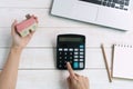 Hand using calculator while holding house model, notebook, and computer laptop,  savings plans for housing financial concept Royalty Free Stock Photo