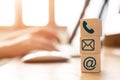 Hand using computer sending message with wooden cube block with icon mail address and telephone symbol