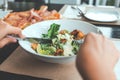 A hand using fork and knife to eat Ceasar salad with pizza on dining table Royalty Free Stock Photo