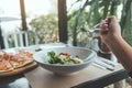 A hand using fork to scoop up Ceasar salad to eat with pizza on dining table Royalty Free Stock Photo