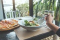 A hand using fork to scoop up Ceasar salad to eat with pizza on dining table Royalty Free Stock Photo