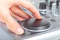 Hand using a generic jog wheel on audio video mixer console or DJ equipment finger adjusting shuttle dial for mixing and playback Royalty Free Stock Photo