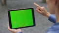 Hand using green tablet outdoors closeup. Girl finger swiping chroma key pad Royalty Free Stock Photo