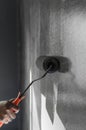 Hand using paint roller applying grey paint on white wall. Royalty Free Stock Photo
