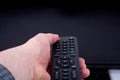 Hand using a remote control in front of the TV screen Royalty Free Stock Photo