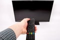 Hand using remote control pushing the power button in front of t Royalty Free Stock Photo