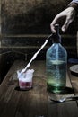 A hand using a siphon bottle to mix soda into glass of wine