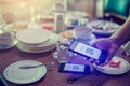 Hand using smart phone to scan QR code on tag with blurry many dishes after eating in restaurant to accepted generate digital pay