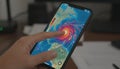 Hand using smartphone tracking hurricane on weather app Royalty Free Stock Photo