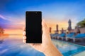 hand using smartphone with view sunrise of swimingpool Royalty Free Stock Photo