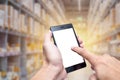 Hand using smartphone with warehouse inventory management technology