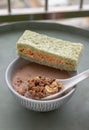 Hand using spoon picking up malt flakes granola in almond milk served with sandwich on ceramic bowl